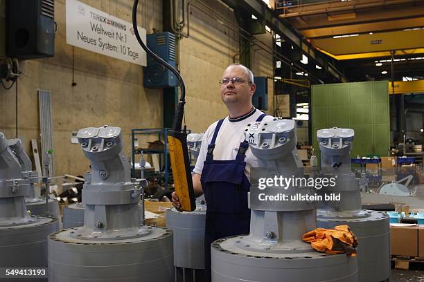 Germany, Dortmund: Swivel motors for a topbase of a Terex O&K hydraulic excavator RH 340. A worker stands behind the swivel motors