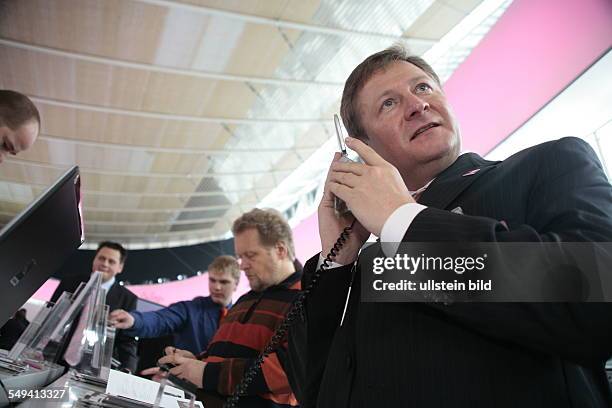 Germany, Hannover, : Cebit 2006.- The exhibition stand of the Deutsche Telekom AG. An interested employee of the Telekom AG testing the MDA Pro...