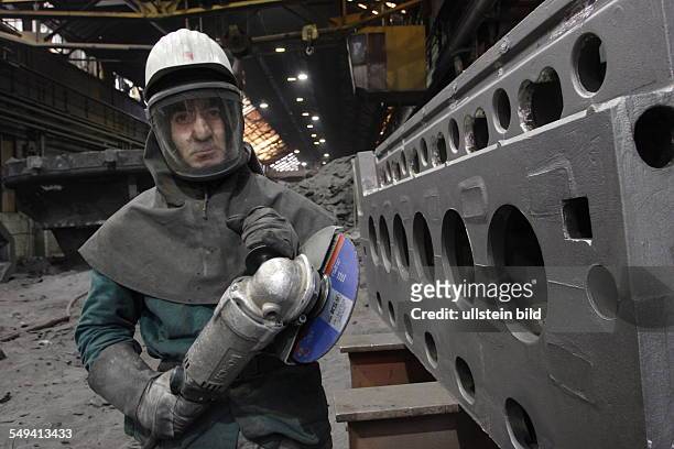 Germany, Muehlheim: The mechanical workshop of the Friedrich-Wilhelm steelworks. A worker in protective clothes with an angle grinder