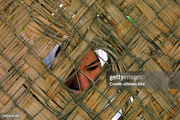 Iraq, Baghdad: The residential quarter Al-Bahadia in the east of the city. A woman behind a fence.