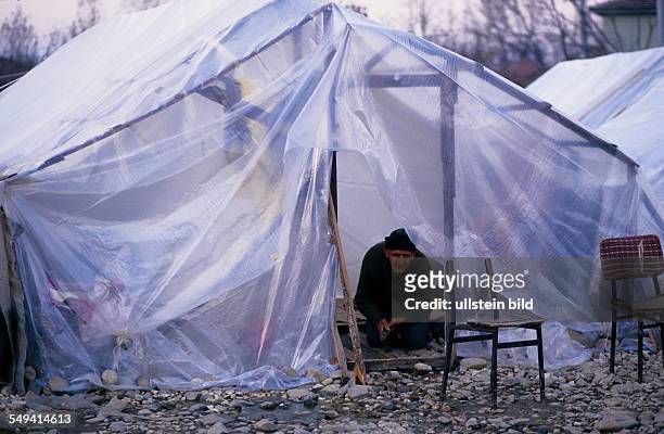 Turkey, Mittelmeer, Duezce: Fater the earthquake.- The provisional accommodation/tent city; a senior citizen working at the lute of the homemade hut.