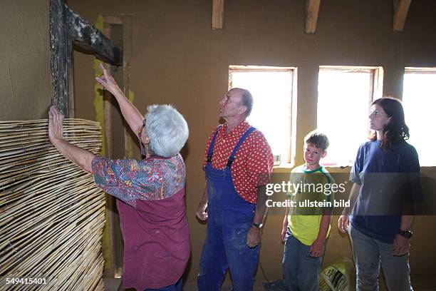 Germany, NRW, Hattingen: A half-timbered house gets completely new renovated. Fixing reeds mats onto walls. The reeds mats serve as carrier material...