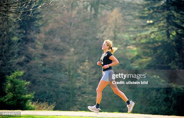 Germany, Essen: A young woman jogging; in the Gruga Park.