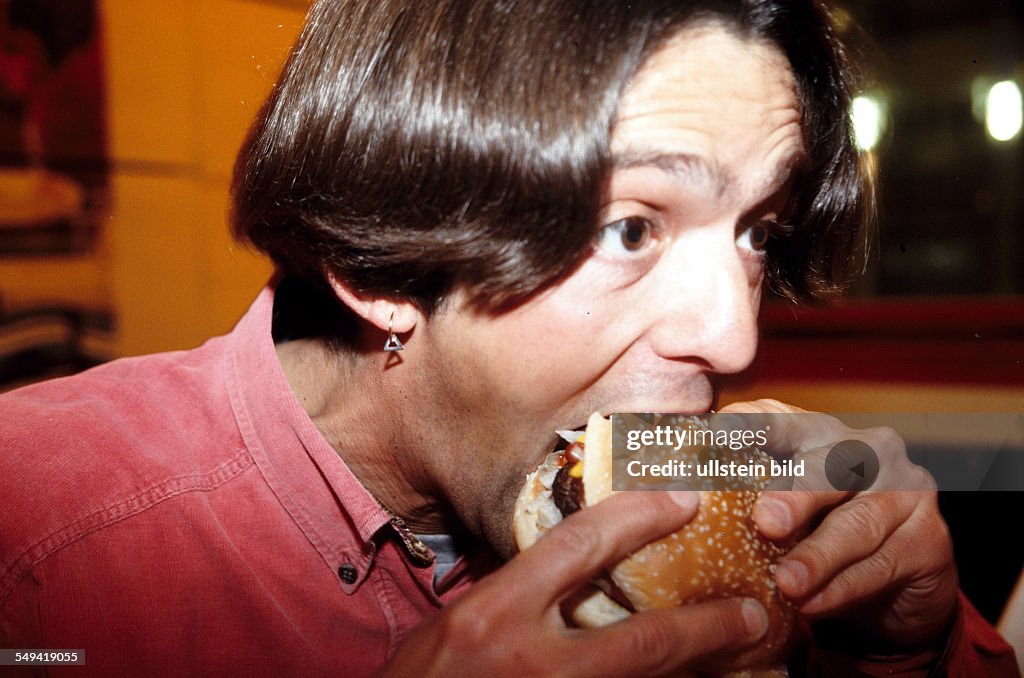 DEU, Germany, Luenen: Food and drinks.- A man eating a hamburg.
