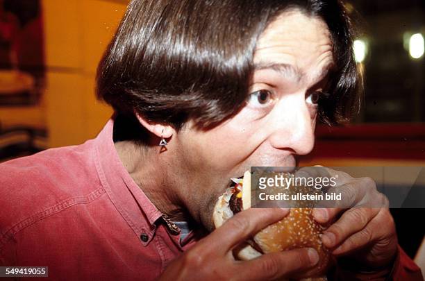 Germany, Luenen: Food and drinks.- A man eating a hamburg.