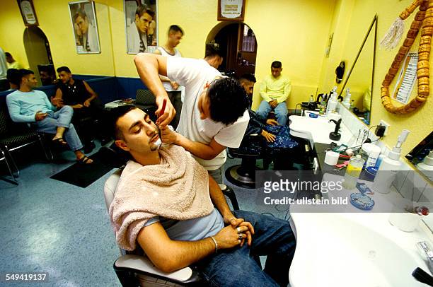 Deutschland, Berlin: Turkish youth at a hairdresser; shaving.