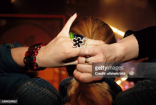 Hands; a young woman tieing up her hair.