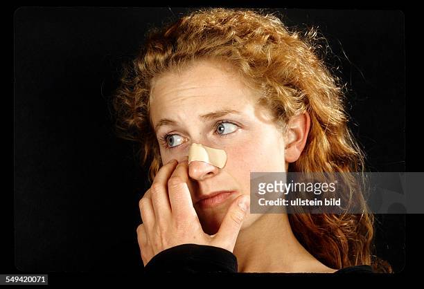 Deutschland: A young woman having a plaster on her nose.