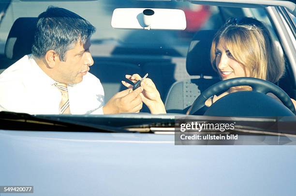 Deutschland, Berlin: VW Audi.- Ali Haydar Berkpinar, turkish salesman handing over the car and the key to a young turkish woman.