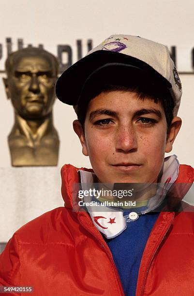 Turkey, Mittelmeer, Adapazari: After the earthquake.- A pupil with his new winter jacket and cap from Germany standing in front of an Atatuerk statue...