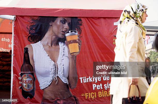 Turkey, Istanbul: a turkish model on the poster advertises for a foreign beer in front of the Carrefour