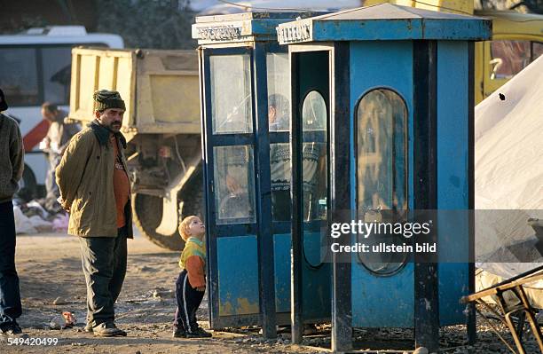 Turkey, Mittelmeer, Duezce: After the earthquake.- A father standing with his child between the ruins in front of a telephone box.