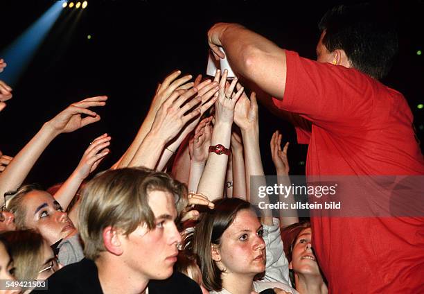 Germany, Dortmund-Hoerde, 1997: YOU 97.- Eins Live-party in Dortmunds Westfalenhalle; security man giving water to the fanatics.