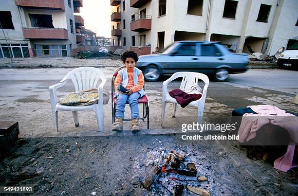 Turkey, Mittelmeer, Duezce: After the earthquake.- A little girl warming herself at the camp fire in the evening; she lives with her family in a tent...