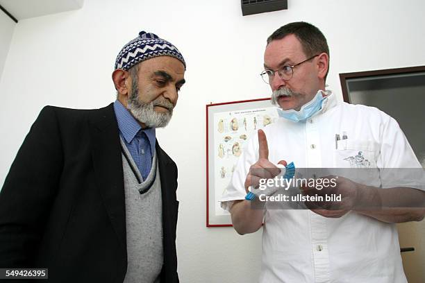 Germany, Luenen: A dental practice.- The dentist is showing how to brush teeth to a Turkish senior citizen.