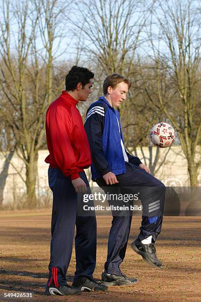 Germany, : Free time/sport.- Two boys on a playing field; one of them is trying to do tricks with a soccer ball.