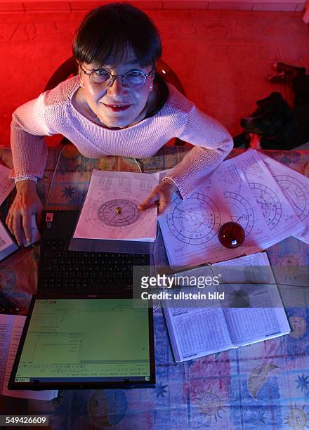 Germany: Portrait of a astrologer working with her notebook and several celestrial charts.