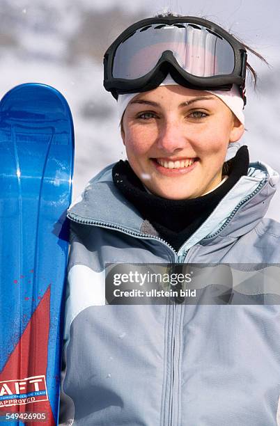 Germany: Free time.- Portrait of a young woman with skies in the snow.