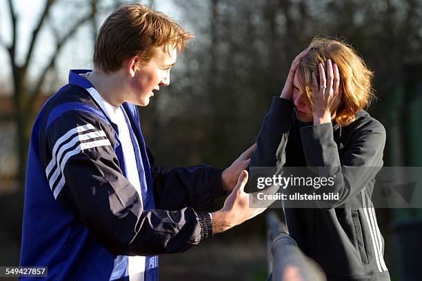 Germany, : Free time/sport.- Two young people diskussing on a playing field; the girl is holding her head.