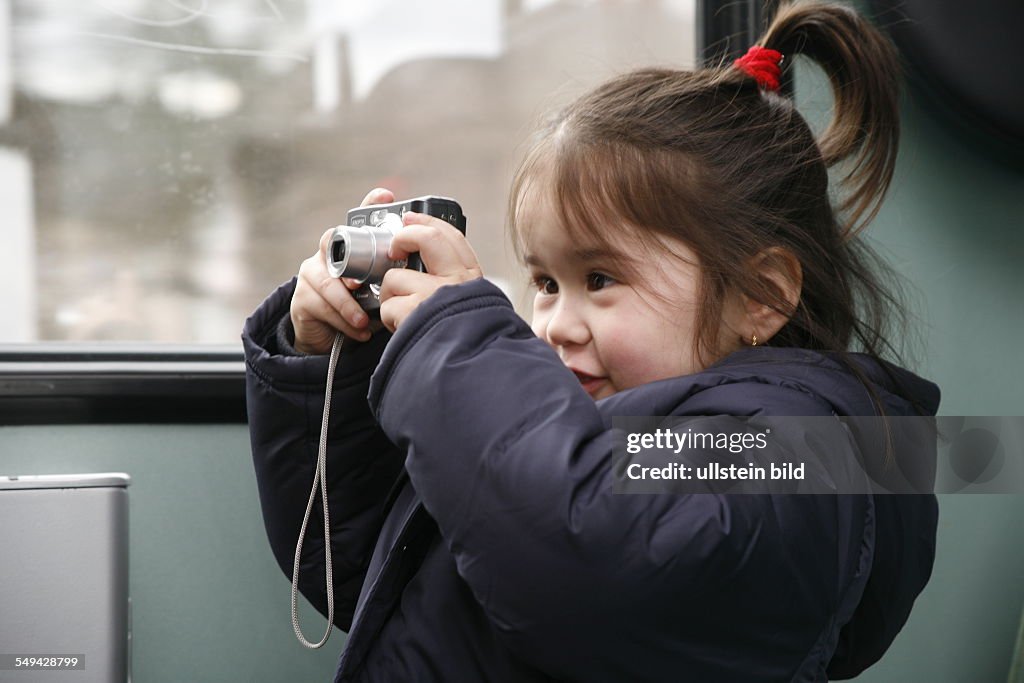 DEU, Germany, Dortmund: In a train.- A 4 years old girl is taking pictures of her mother and friends with a digital camera.