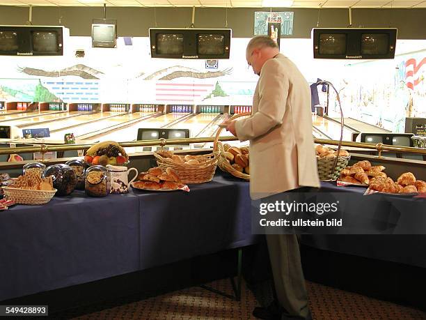 Germany: Bowling alley.- A man helping himself on the breakfast buffet.