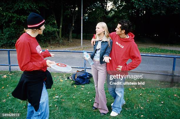 Germany: Free time.- Three youth in a park; they are talking, one of them is holding a frisbee.