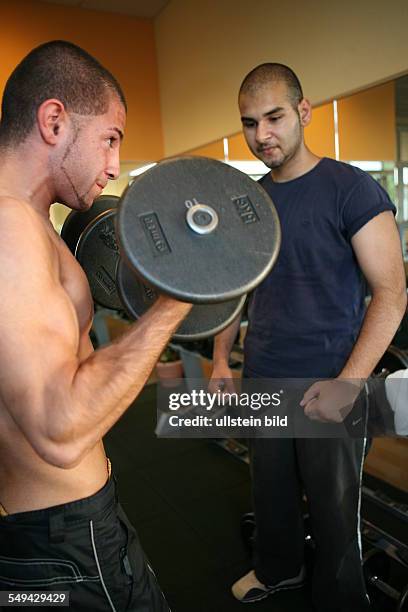 Germany, Wesseling: 2 young turkish men during their practise in a fitness studio. Joerg Boerjesson advices and informs them about anabolic steroids...