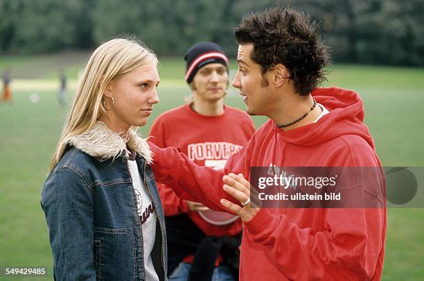 Germany: Free time.- Three youth on a meadow; two of them are talking.