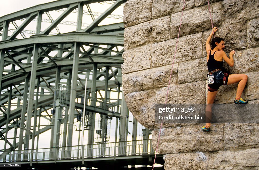 DEU, Germany: Free time.- A young woman climbing up a stone wall.