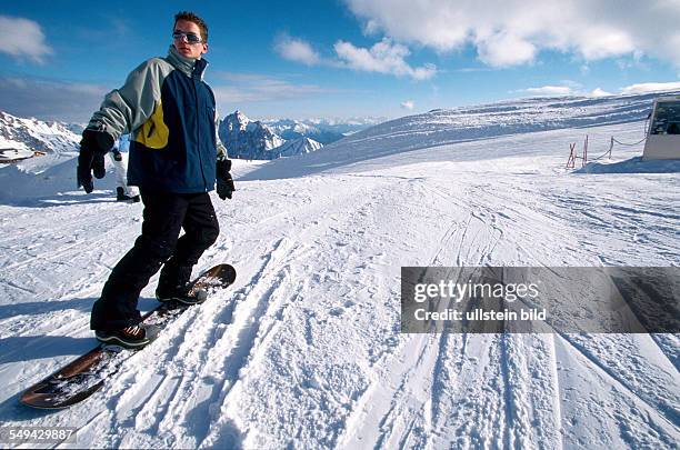 Germany: Free time.- Young persons snowboarding in the mountains.