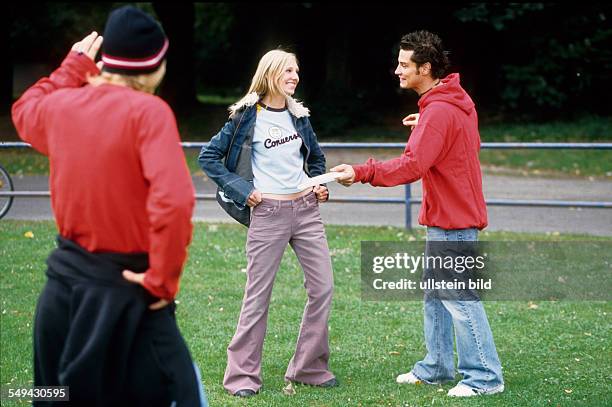 Germany: Free time.- Three youth meeting in a park; they are talking.
