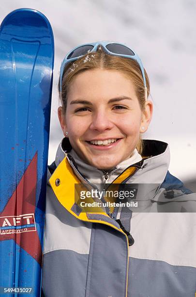 Germany: Free time.- Portrait of a young woman in the snow; she is holding a snowboard.