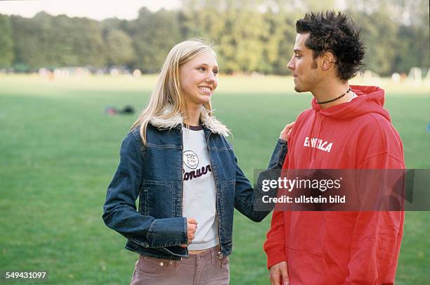 Germany: Free time.- Two youth on a meadow; they are talking and flirting.