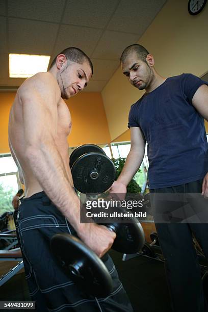Germany, Wesseling: Two young turkish men during their practise in a fitness studio. Joerg Boerjesson advices and informs them about anabolic...