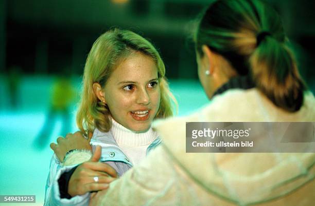 Germany: Free time.- Two young girls in an ice-skating rink; they are talking.