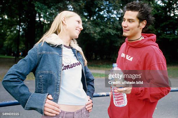 Germany: Free time.- Two youth on a meadow; they are talking and flirting.