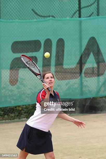 Germany, : A young woman playing tennis.