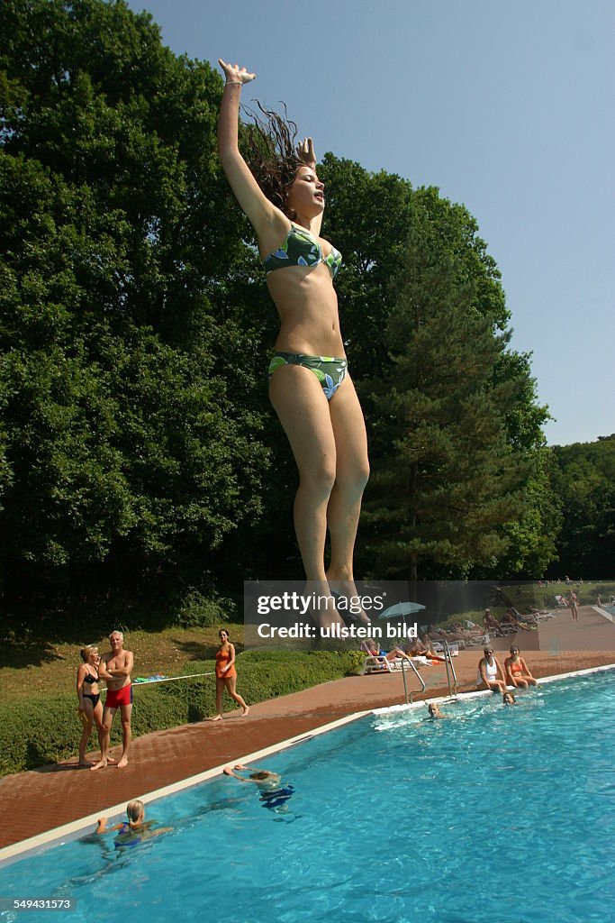 DEU, Germany, 11.10.2003: In a swimming pool; a young woman jumping into the water.