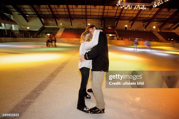 Germany: Free time.- A young couple skating in an ice-skating rink; they are kissing.