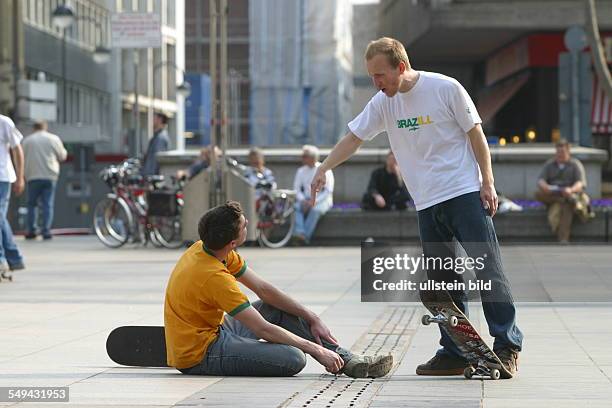 Germany, Cologne: Youth in their free time.- Young men skateboarding on the square in front of the cathedral; argument after a fall.