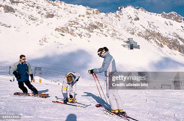 Germany: Free time.- Young persons skiing and snowboarding in the mountains.