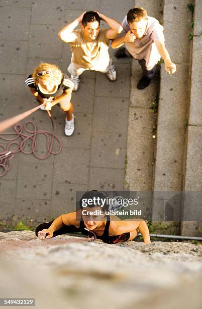 Germany: Free time.- Young persons climbing; a women is climbing up a stone wall.