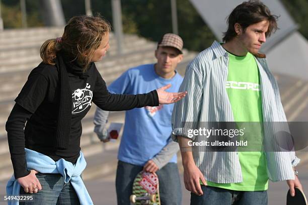 Germany: Young persons in their free time.- Skateboarding; discussion between a young couple, another friend standing in the background.