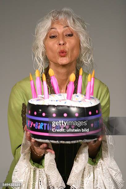 Germany: Portrait of a woman; with a fancy dress and a plastic birthday cake in her hands.