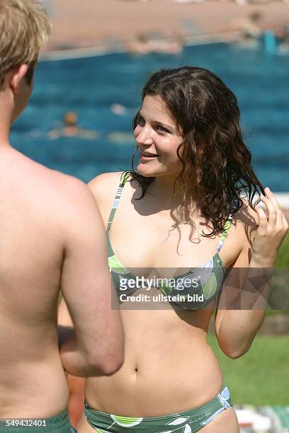 Germany, : Youth in a swimming pool; a young woman and a young man talking.