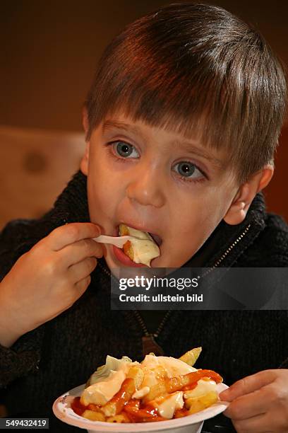 Germany: Portrait of a little boy eating chips.