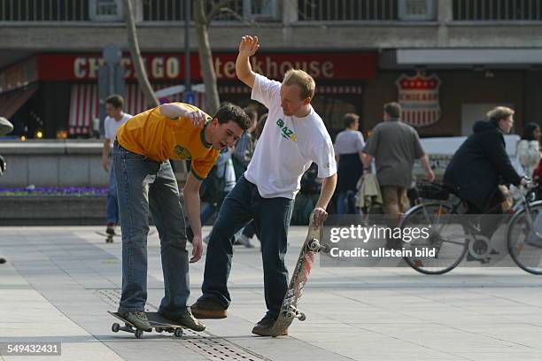 Germany, Cologne: Youth in their free time.- Young men skateboarding on the square in front of the cathedral.