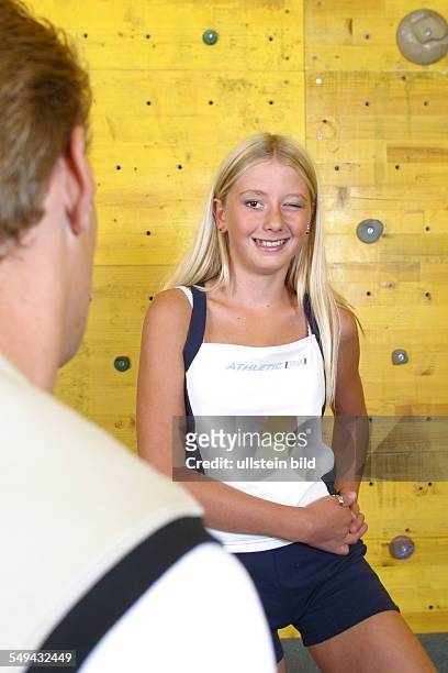 Germany, : Free time/sport.- In front of a climbing wall; a girl is winking to a boy who is standing opposite her.