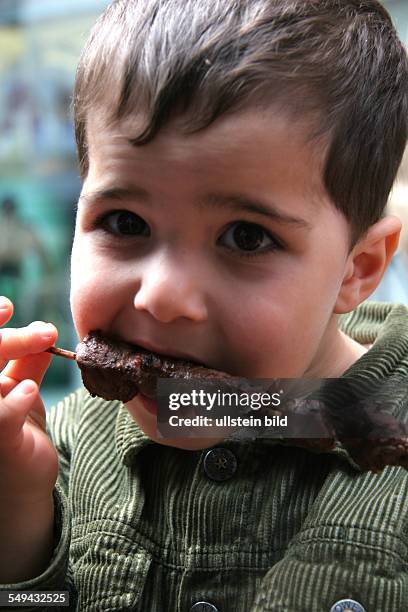 Germany: child eats spit-roast lamb in the city