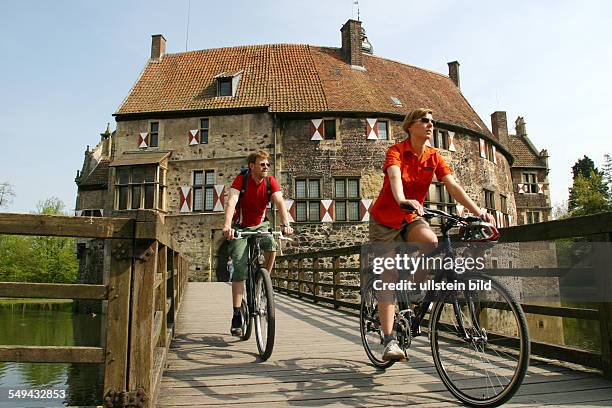 Germany: Bicycle tour through the Muensterland.- Over an old wooden bridge to Vischering Castle in Luedinghausen.